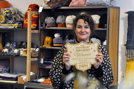 Beck Prior holding the Holly Tucker award. Background is of the shop display. 