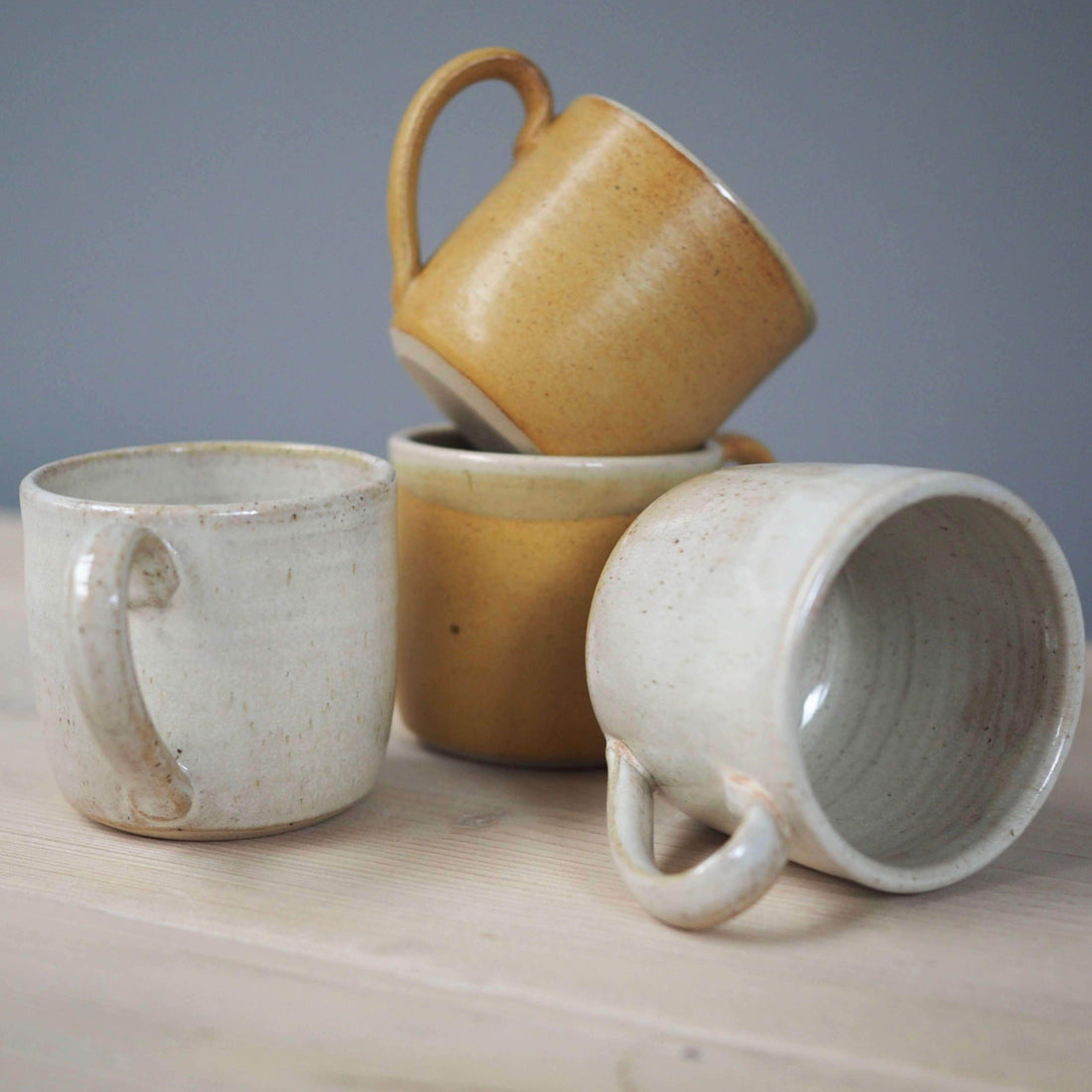 Collection of handmade coffee mugs in mustard and white 